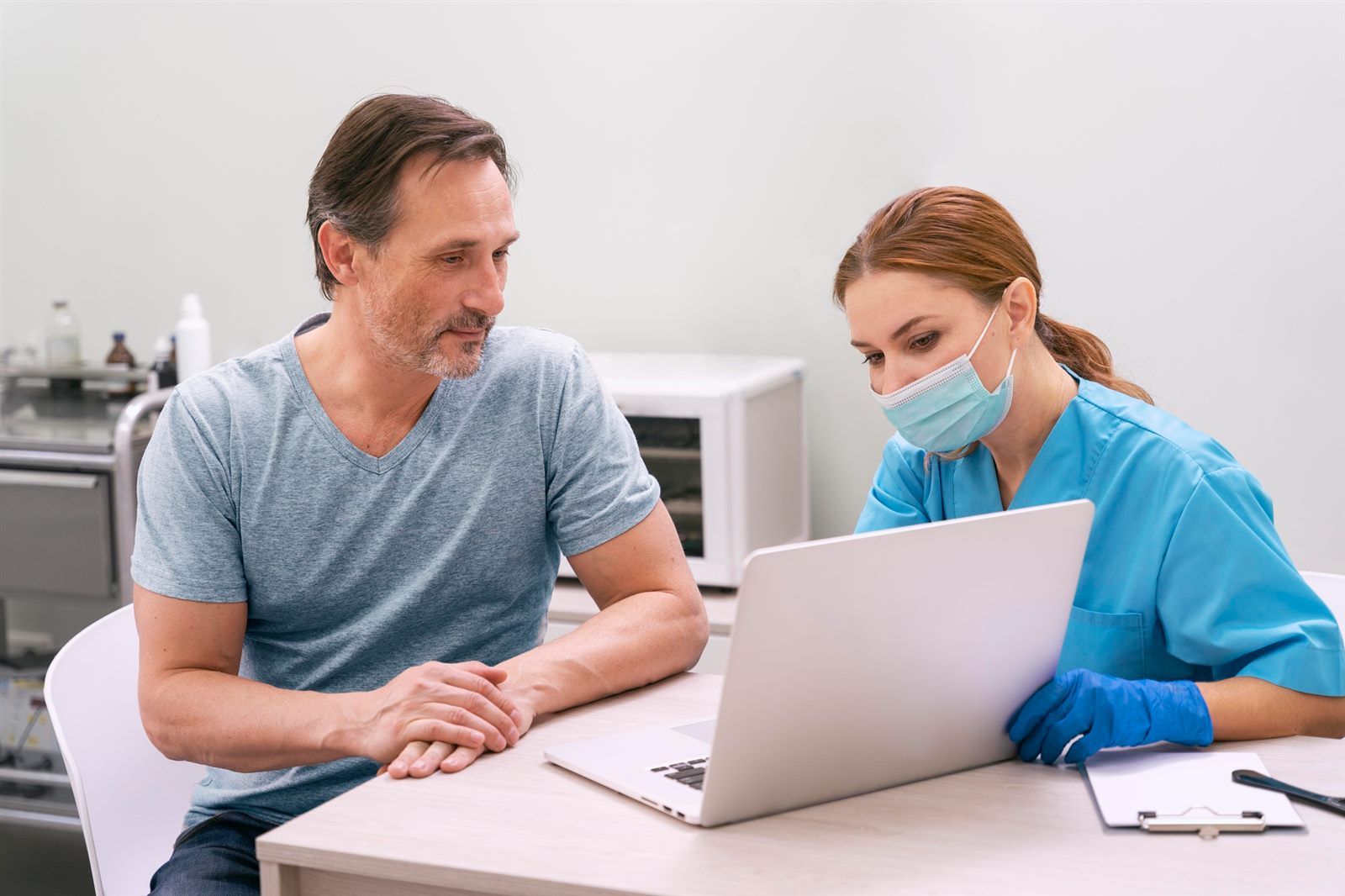 Patient reviewing his health records on a laptop with a nurse