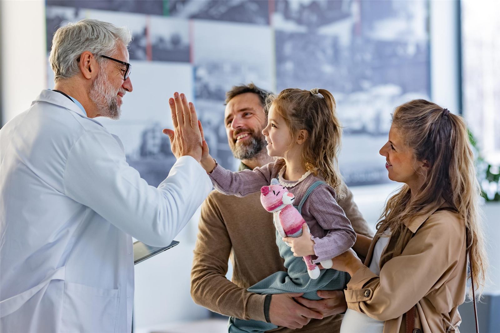 Family medicine doctor greeting a young patient and her parents
